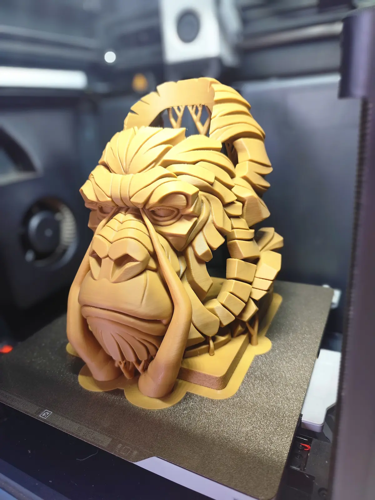 Large geometric lion head 3D printed sculpture displayed on a printer build plate